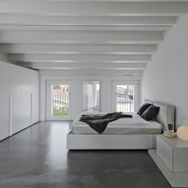 modern bedroom in the attic room with resin floor and wooden ceiling